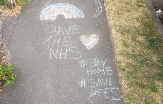 Bildet viser en krittegning på asfalten hvor det blant annet står Save the NHS