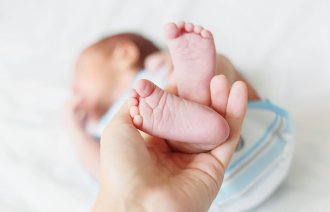 Føttene til nyfødt baby løftes opp