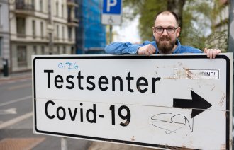 Bildet viser Daniel Kendrick ved et skilt som viser veien til teststasjonen.