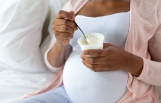 Bildet viser en gravid kvinne som spiser yoghurt