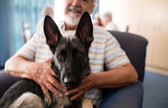 Bildet viser en eldre mann med en hund på fanget.