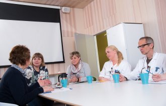 Bildet viser tverrfaglig helsepersonell som har møte rundt et bord.