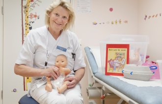 Bildet viser Astrid Ingeborg Austrheim som holder en dukke med pose på magen.