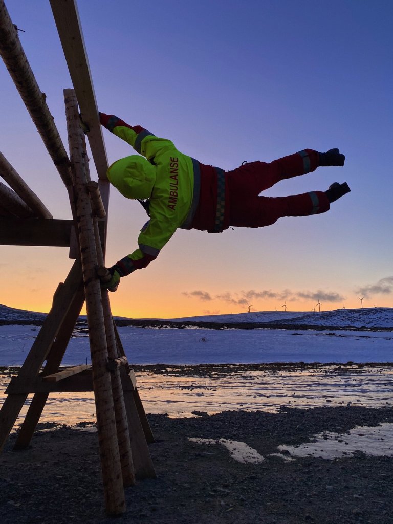 Bildet viser en ambulansearbeider som holder seg fast i vinden.