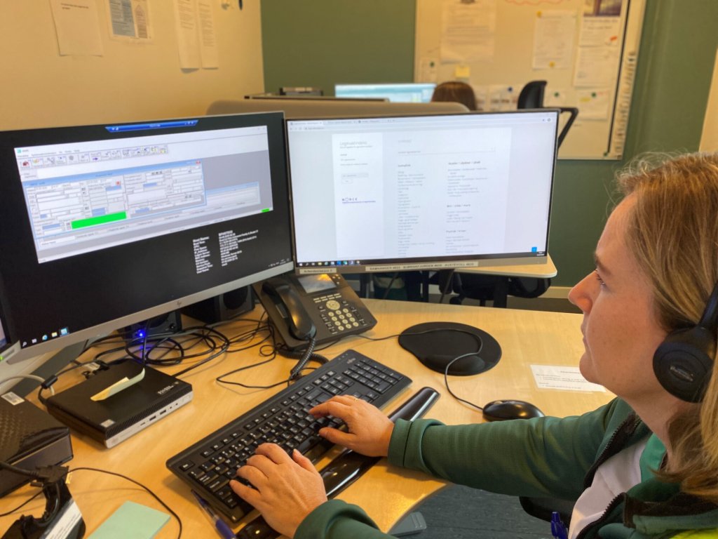 Bildet viser en sykepleier som sitter og ser på skjermer på en legevaktsentral.