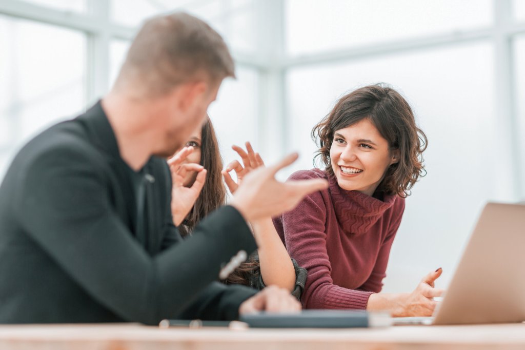 En mannlig og to kvinnelige studenter diskuterer foran en datamaskin.