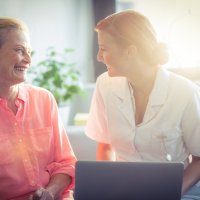 En sykepleier og en pasient smiler til hverandre