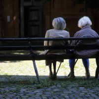 Bildet viser to eldre kvinner som sitter på en benk